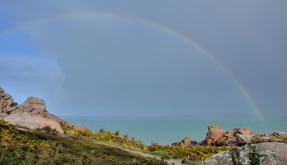Rainbow over the pink granit coast at Ploumanach in Brittany. France