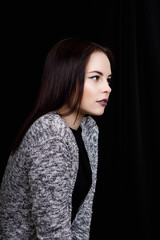 Portrait of cute woman which is looking to the side. Full face on a black background