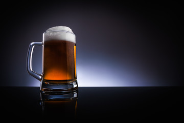 A glass of beer, with a handle, on a dark background