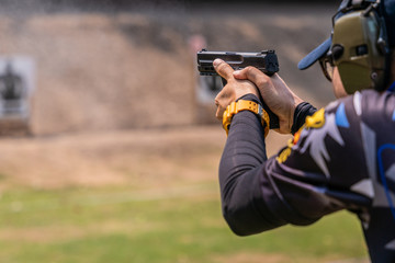 selective focus of man holding and fire handgun in gun shooting competition - obrazy, fototapety, plakaty