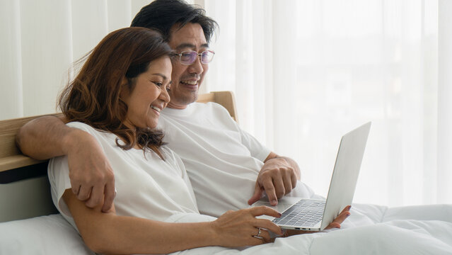 Asian Couple Happy Together Using Laptop Computer On Bed