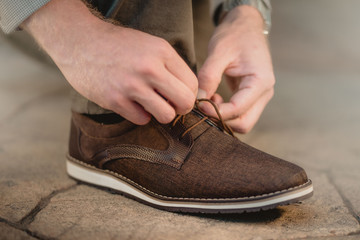 Hombre amarrando las agujetas del zapato café