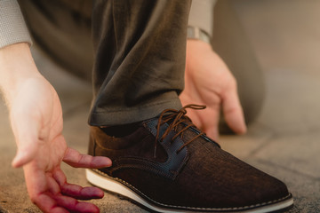 Hombre amarrando las agujetas del zapato café