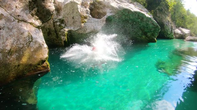 Man enyoing canyoning jump into the emerald river from the rock