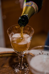 Pouring a bottle of fizzy champagne into a crystal wine glass. New year celebration and refreshing drinks at a party