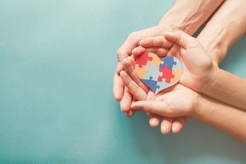 Adult and chiild hands holding jigsaw puzzle heart shape, Autism awareness, Autism spectrum disorder  family support concept, World Autism Awareness Day