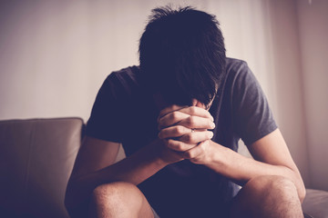 Depressed, and anxiety young man sitting alone and praying at home, social distance, mental health,...