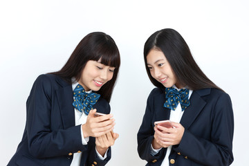 スマートフォンを持つ女子学生2人