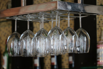 Glass for put wine hanging upside down on a rail at the counter bar.
