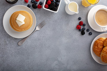 Breakfast table overhead with copyspace, pancakes and croissants with fresh berries and coffee