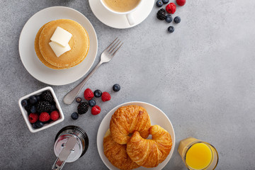 Breakfast table overhead with copyspace, pancakes and croissants with fresh berries and coffee