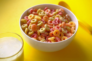 close up of ring corn flakes in a bowl on yellow background 