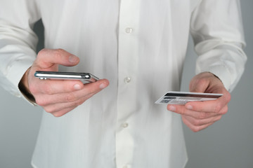 Man holds credit card and phone in his hands.