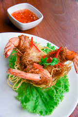 Goong Sarong  noodles Wrapped Shrimp With Crispy Noodle Serve, vegetable and sauce in white plate  on wood table , Thai food