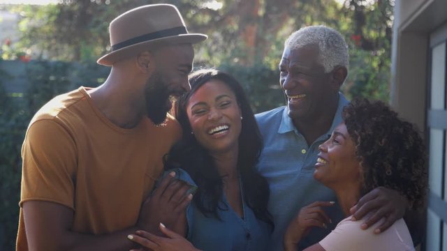 Portrait Of Senior Parents With Adult Son And Daughter Relaxing In Garden At Home