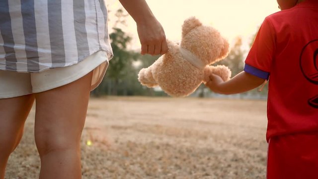 Close-up Hand of Asian mother and her daughter holding teddy bear's  hands and walking together. Mother and child with love and relationship concept.