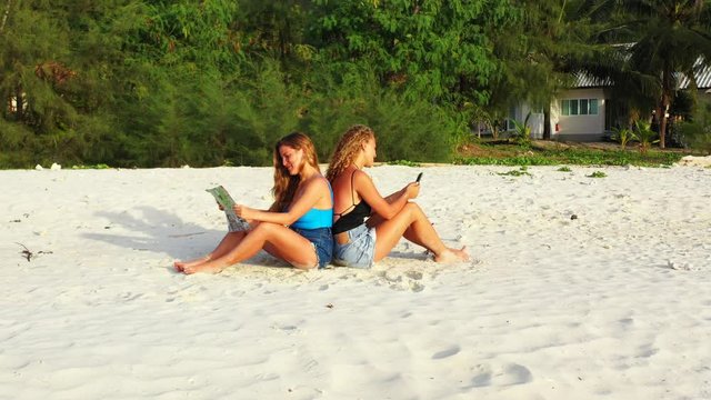 Close up. Dreamhouse on the sandy beach and young ladies relaxing on the tropical island.Thailand