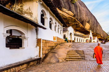 A buddhist monk is walking along the Rock cave temple , a world heritage site in Dambulla,  Sri Lanka