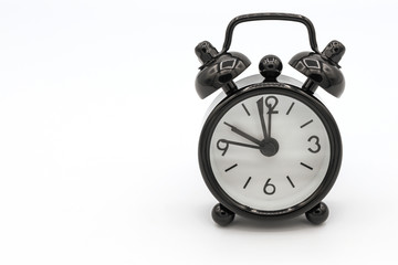 A black retro alarm clock isolated on white background. Alarm clock used to awaken people from their night's sleep or short naps.