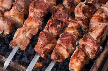 Meat skewers on grill roasted on fire, delicious roast pork close up