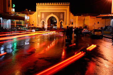 Car taillights reflected on wet Place Boujeloud with Blue Gate Morocco at night