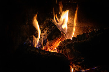 Closeup of last moments of firewood burning in fire with dimly flames light and enclosing shadows. Concept of tranquility, relaxation and silence.