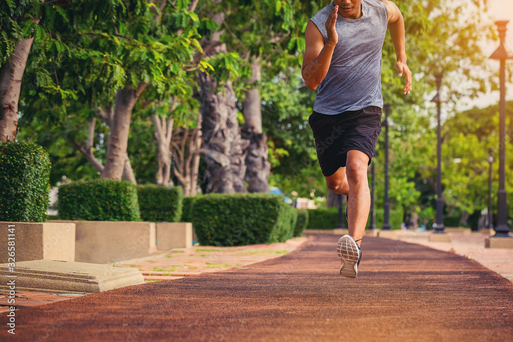 Wall mural Man running sprinting on road. Fit male fitness runner during outdoor workout in the park. Selected focus - Wall murals