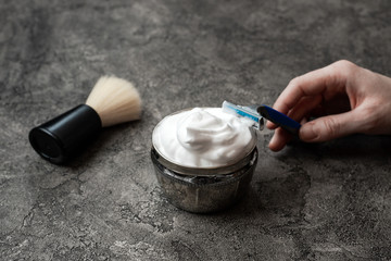 Hand holds disposable razor on gray wall background