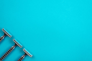 Three disposable razors are arranged diagonally on a blue background.