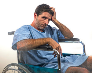 young depressed and frustrated injured man in hospital patient gown desperate and upset at...