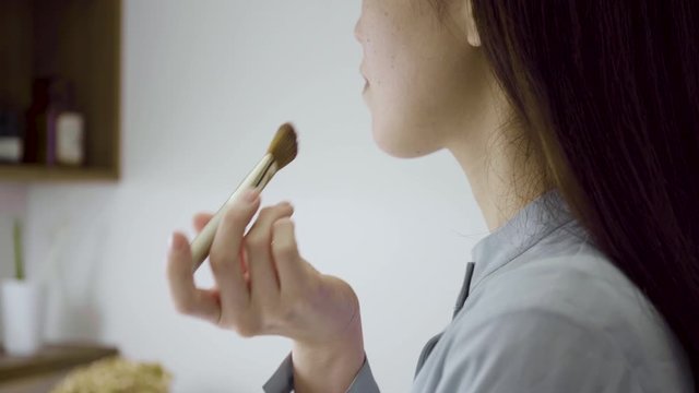 洗面化粧室でメイクをする若い女性