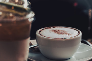Close-up a white cup of coffee placed on the table in a cafe and vintage style.