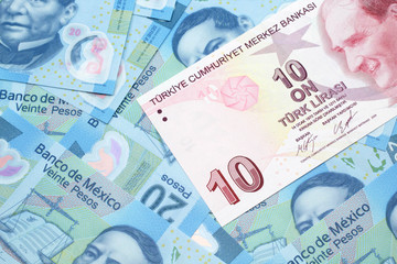 Fototapeta na wymiar A close up image of a red ten Turkish lira bank note on a background of Mexican twenty peso bank notes in macro