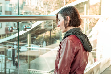 Woman with brown hair watching the street through the window