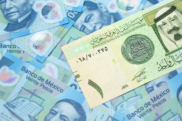 A close up image of a one riyal bank note from Saudi Arabia on a background of Mexican twenty peso bank notes in macro