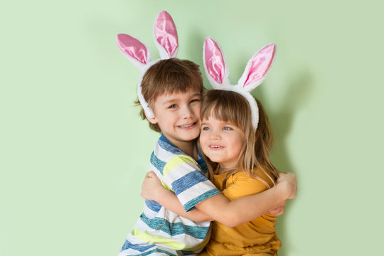 Two kids brother and sister wearing bunny ears Hugging on a green background. Happy easter!