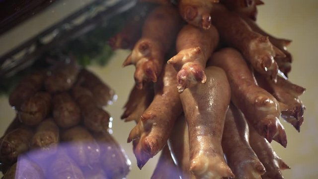 Pan shot of lots of ham hocks pig's trotters hanging in an Italian butchers during Christmas winter holidays.
