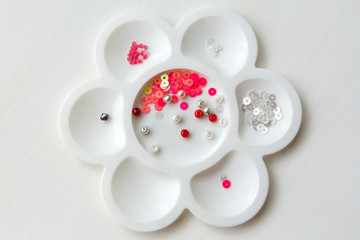 a set of beads and sequins in a container in the form of a flower