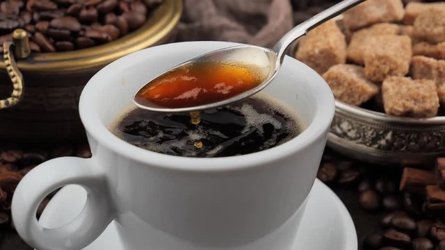 Mixing steaming coffee in a cup with a spoon