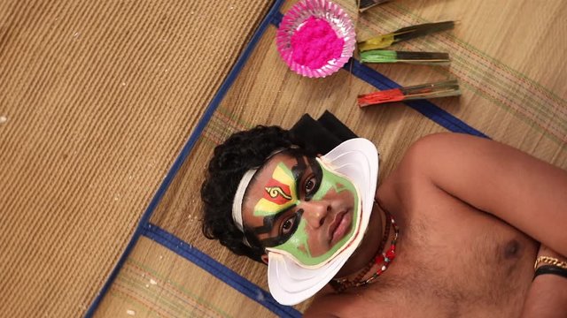 Kathakali dancer lying on the chatai and looking upwards. 