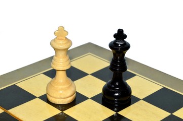 Two wooden varnished chess pieces of kings next to each other on the background of checkerboard corner