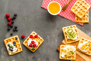 Breakfast with freashly baked belgian waffles on grey background top-down frame copy space