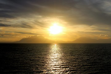 Obraz premium evocative image of sunset over the sea with headland silhouette in the background
