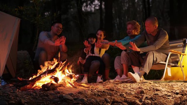 Happy Family Around Burning Camping Bonfire In The Woods And Smiling Together. Nature Tourism Concept.