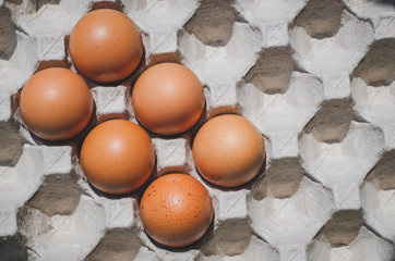 Chicken eggs in a cardboard tray packaging with vintage tones top view close-up.
