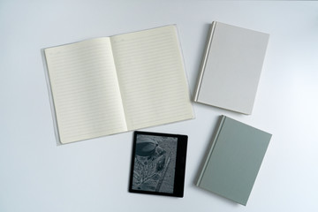 Books and notebooks and kindle eBooks on white desktop