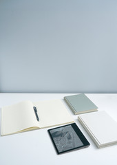 Books and notebooks and kindle eBooks on white desktop