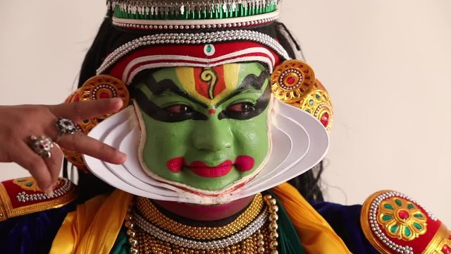Close up of a Kathakali dancer doing a neck movement with a mudra.
