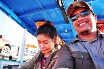 Happy tourist couples traveling by boat to visit the island at the fishing port.