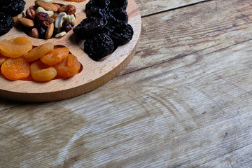 Dried apricots, prunes and nut mix at weathered wooden background